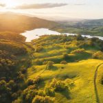 An aerial view of a green valley with a lake