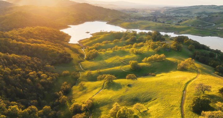 An aerial view of a green valley with a lake