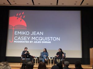 Emiko Jean and Casey McQuiston sit on stage inside of the Portland Art Museum.