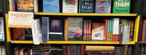 Shelf lined in orange with books to donate to the library.