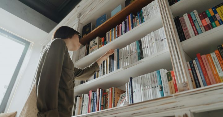 Person touching books on a bookshelf