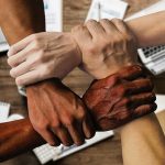 image of four hands linked together to illustrate diversity and teamwork
