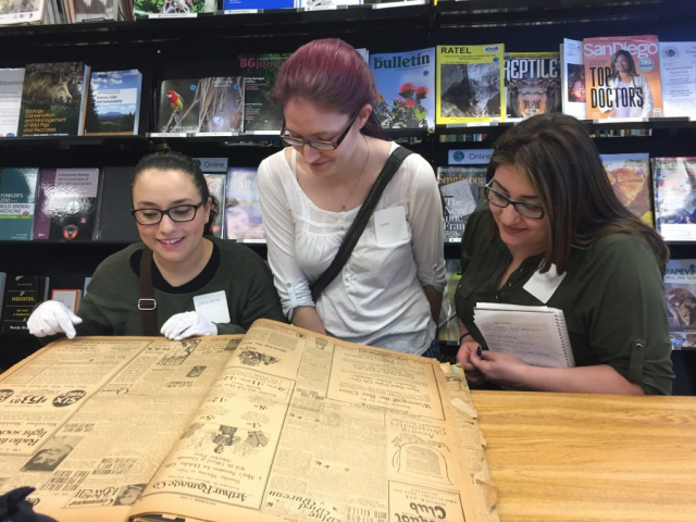 Three students looking through an old book.