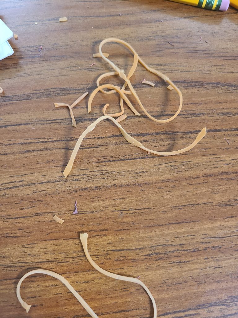 Pieces of rubber bands on a brown table.