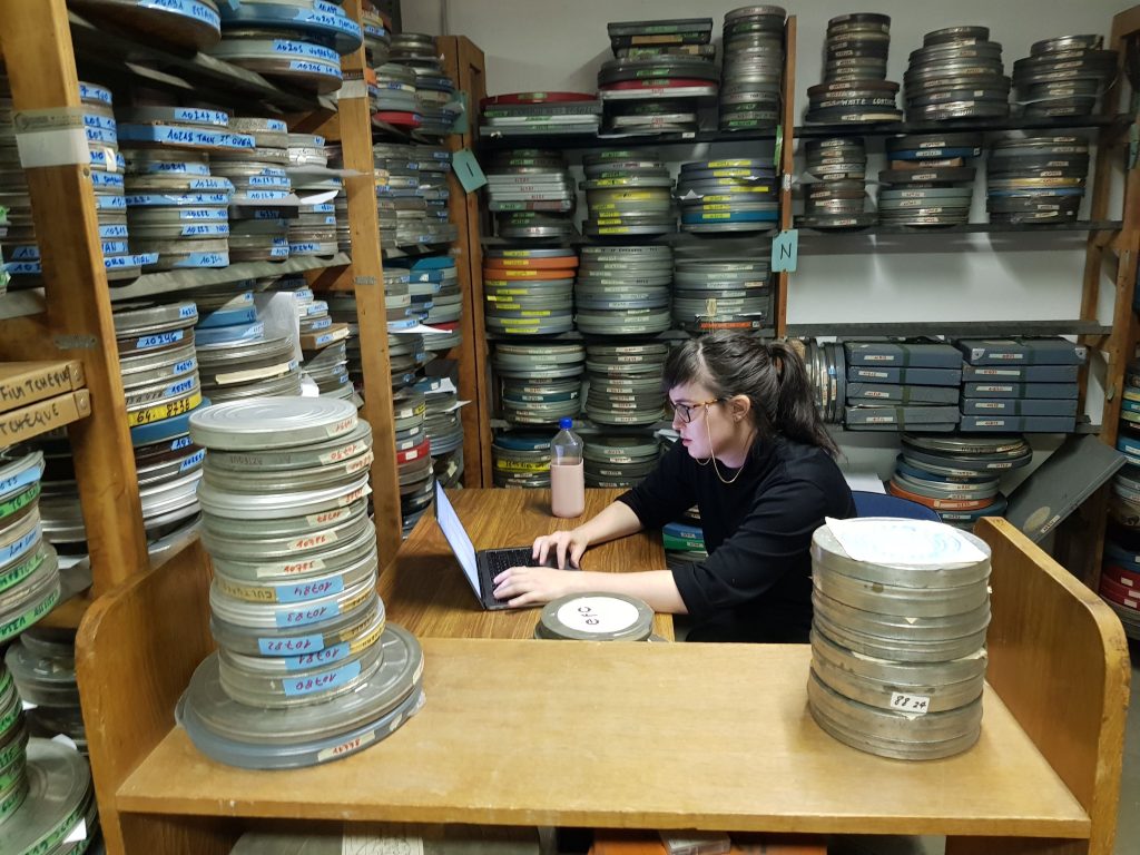 An archivist surrounded by reel-to-reel film.